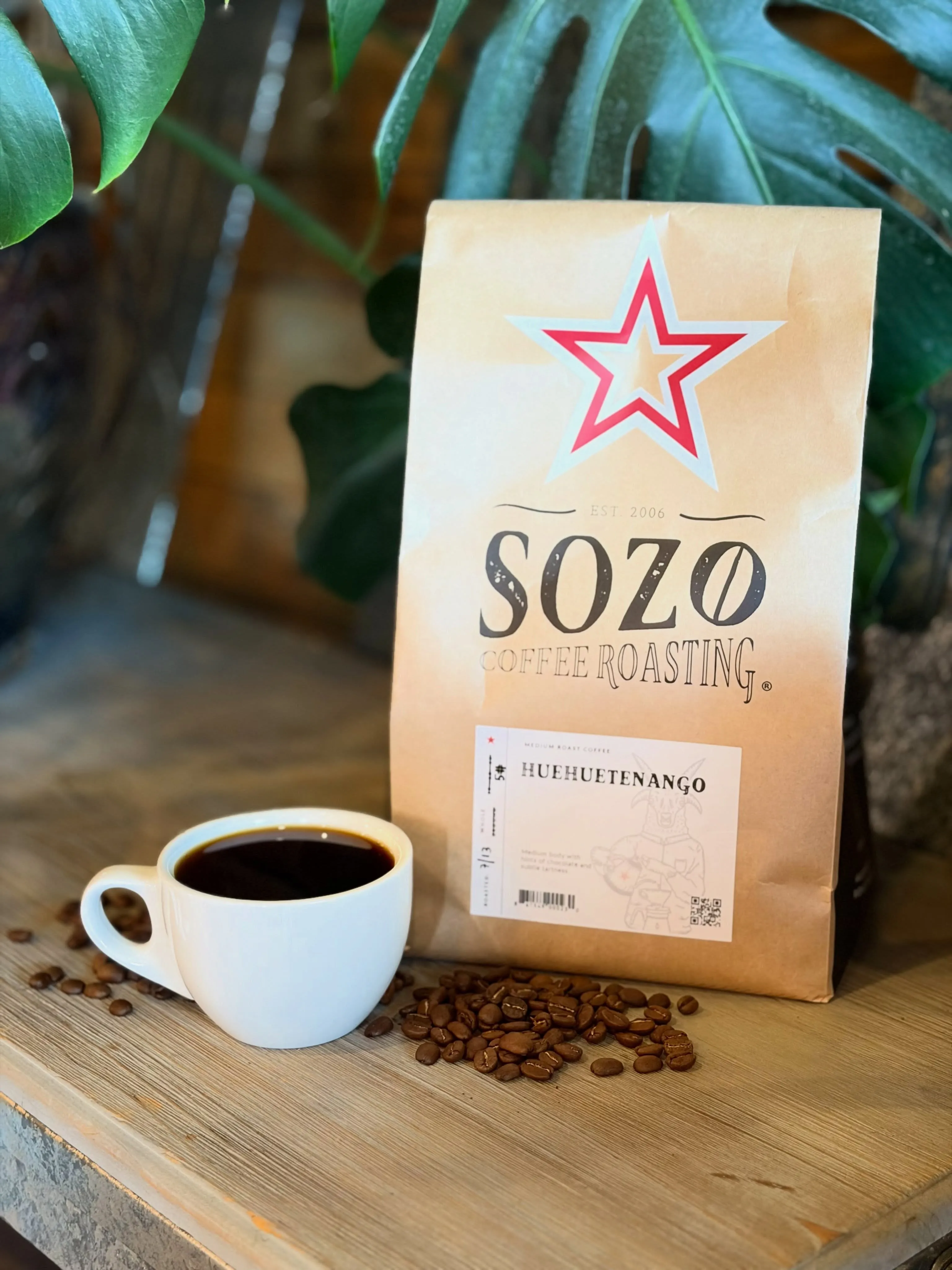 A bag of Sozo Coffee Roasting beside a cup of black coffee